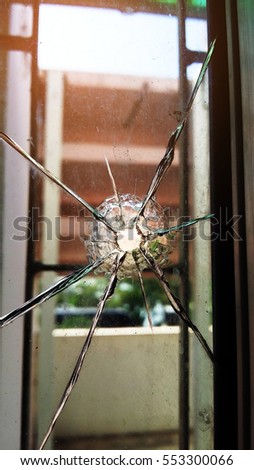 Broken window with a bullet hole in the middle.