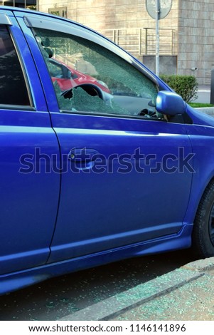 Broken window from driver's side. Attempt to steal bluecar. criminal situation in russian city. splinters of glass on asphalt