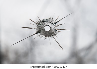 Broken window glass with a bullet hole 