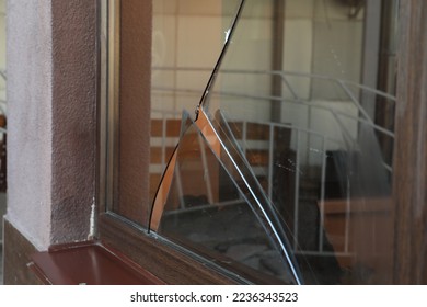 Broken window with sharp smithereens outdoors. Requiring repair