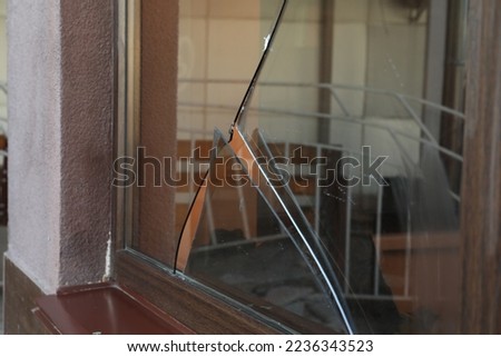 Broken window with sharp smithereens outdoors. Requiring repair