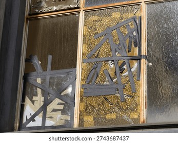 broken window that has been provisionally secured with tape