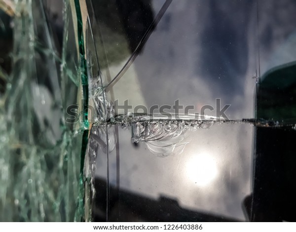 Broken windshield of abandoned and destroyed car,\
with broken glass.