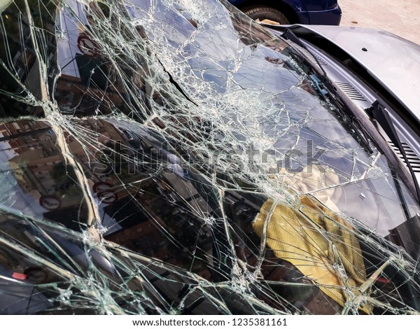 Broken windshield of abandoned and destroyed car,\
with broken glass.
