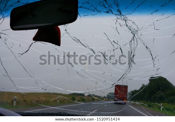 Broken windshield in the car, accident\
on the road with oncoming traffic, dangerous\
driving.