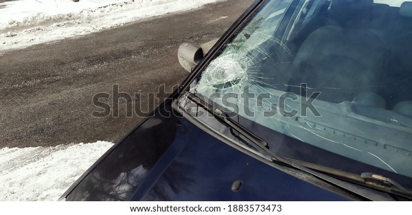 Broken windshield of a car, close-up.
Careless driving, stone hit the glass of the car.
