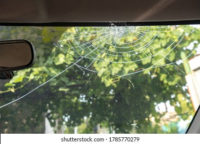 broken windshield with a lot of cracks and small glass pieces, damaged car