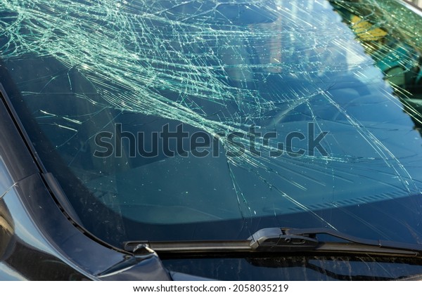 broken\
windshield on a car, crushed iron fender of a\
car
