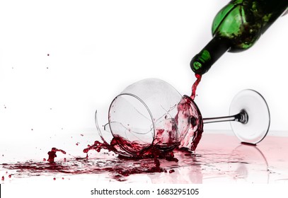 broken wine glass on a quilted table isolated on white background. red wine spills from shards