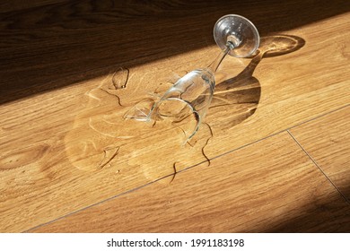 Broken Wine Glass On A Wooden Floor At Home. The Problem Of Alcoholism In The Family, Alcoholic Anonymous, Concept Image.