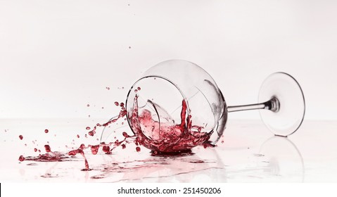 Broken wineglass on the table. Poured red wine, like blood.