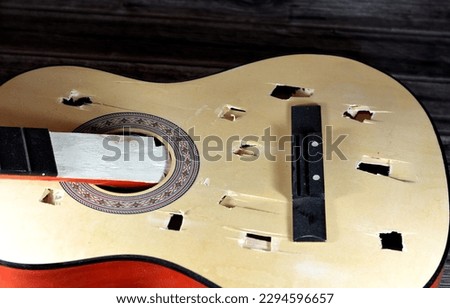 A broken wooden old classic guitar with damaged strings chords, shattered musical instrument, unattached damaged guitar with cut chord and wood, selective focus of non working music instrument Stockfoto © 