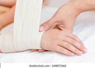 Broken Wrist With Bandage In Hospital Office. Doctor Is Bandaging Limb Of Patient. Sprain, Stress Fracture, Trauma In Hand. Child Broken Arm. Nurse Helping Customer. First Aid.