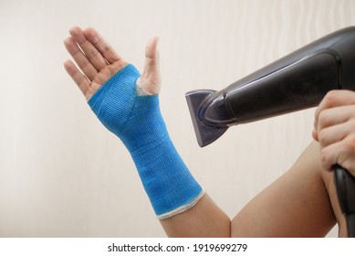 Broken Wrist In A Modern Waterproof Bandage. Male Hand Wrapped In Fiberglass Plaster Cast Dries With A Hairdryer