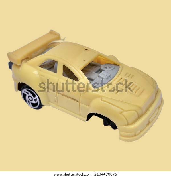 Broken yellow plastic car toy on the yellow\
colr background