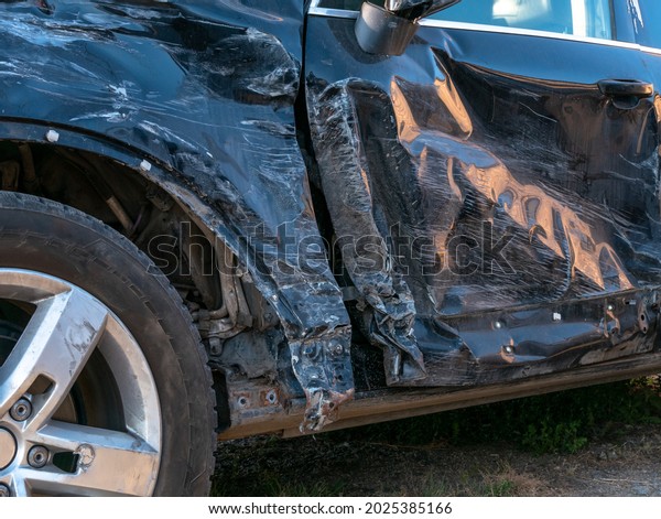 A broken-down car after an road accident.\
Damage to the side of the car, close\
up.