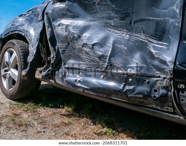 A broken-down car after an\
road accident. Damage to the side of the car and dented door, close\
up.