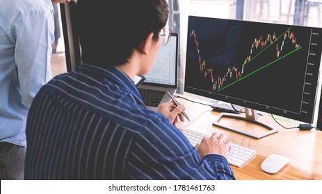 broker showing some ascending to his colleague planning and analyzing graph stock market trading with stock chart data on multiple computer screens - Shutterstock ID 1781461763