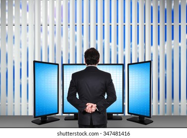 Broker Standing In Office And Looking To Four Blank Monitor