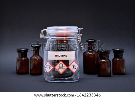 Bromine bottle stock images. Toxic liquid stock images. Brown lab bottle. Brown glass container. Phial with warning pictograms on a black background. Laboratory accessories