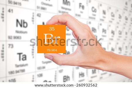 Bromine symbol handheld in front of the periodic table