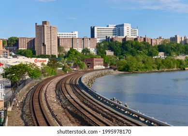 Bronx, NY USA - May 15, 2021: Amtrak and Metro North train tracks curve along the Harlem River in Bronx, NYC. The white building in the background is the Bronx Veterans Medical Center