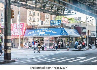 Bronx, USA - June 11, 2017: Road and street under subway railroad with restaurants and shops with sidewalk in downtown Fordham area