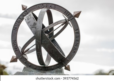 A bronze armillary sphere dial isolated on bright sky background. Brass armillary sphere on a stone pedestal.