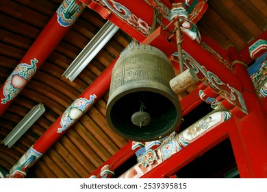 A bronze bell hangs from a red wooden beam, surrounded by ornate decorations and colorful patterns. Chinese word means Bell. - Powered by Shutterstock