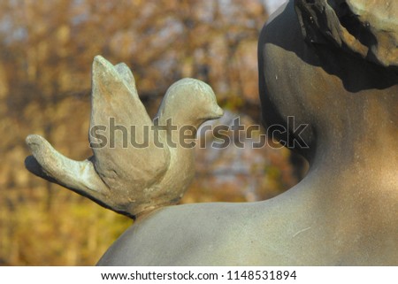bronze boffin statute from behind of girl with bird on her shoulder