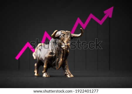 Bronze bull figurine in front of a graph with an arrow indicating uptrend in business and markets
