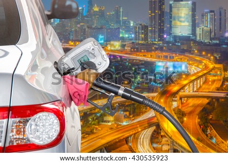 Bronze car at gas station being filled with fuel and the blurred bangkok expressway and highway top view background, Transportation Concept, selective focus