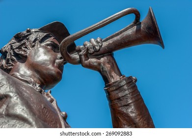 Bronze cast statue with brown patina of an American Civil War soldier playing the bugle.