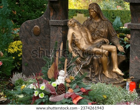 Bronze grave figures, cemetery in autumn on All Saints' Day, autumn flower arrangement, grave decoration for winter, fallen leaves in autumn