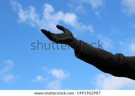 bronze hand near the statue against the sky
