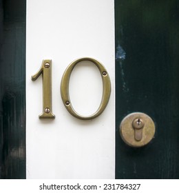 Bronze house number ten. Separate numerals on a doorpost