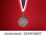 Bronze medal with striped ribbon on red background