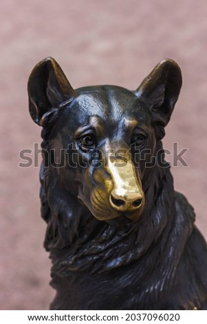 Bronze sculpture of a dog with a polished nose.