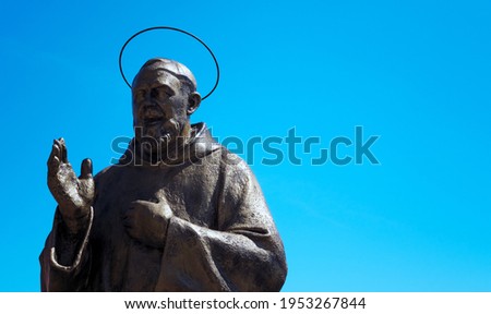 bronze statue of Padre Pio with blue sky in the background