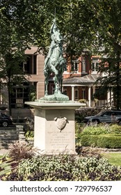 Bronze Statue Of Sancta Joanna D Arc - Joan Of Arc Stands As A War Memorial In A Colorful Garden On A Sunny Day