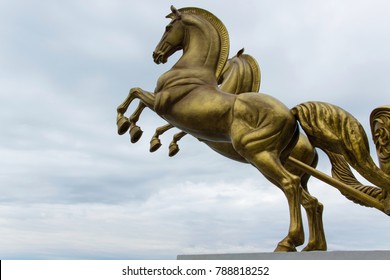 Bronze statue of two horses in motion with sky background and space for text