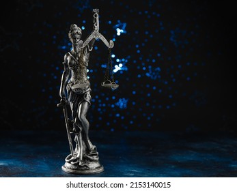 Bronze Statuette Of The Goddess Of Justice Themis On A Dark Blue Background. Court, Advocacy, Democracy, Rule Of Law, Justice. There Are No People In The Photo. Minimalism.