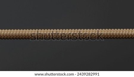 Bronze twisted guitar string against a dark background. Macro photography.
