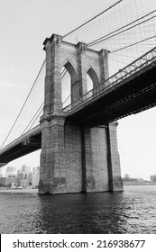 Brooklyn Bridge black and white over East River viewed from New York City Lower Manhattan waterfront.