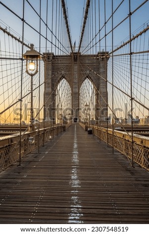 The Brooklyn bridge early in the morning dawn and lighting lamps.