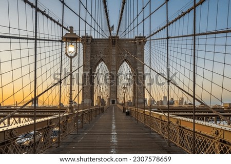 The Brooklyn bridge early in the morning dawn and lighting lamps.