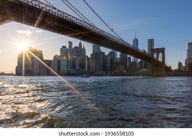 Brooklyn Bridge, East River And Lower Manhattan In Background. NYC Skyline. Bright Sunny Day And Sunlight. Dumbo. Sightseeing Place Among Locals And Tourists In NYC.