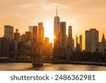 Brooklyn Bridge and New York City skyline across the East River illuminated by an intense, fiery sunset.