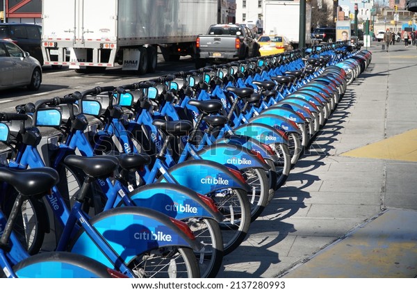 Brooklyn, NY; Circa 2022:\
Citibike ride share bicycle rack outside on sidewalk during morning\
commute. New York commute traffic passes by on  Avenue in\
background