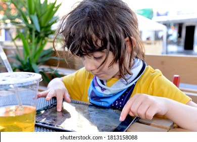 Brooklyn, NY, US - July 15, 2020: A Young Elementary School-age Girl Presses With Her Index Fingers On An Apple IPad Tablet Device At An Outdoor Restaurant During The COVID-19 Pandemic.